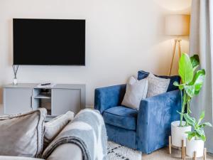 a living room with a blue couch and a tv at The Coach House in Whittonstall