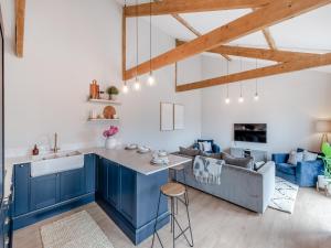 a kitchen with blue cabinets and a living room with a couch at The Coach House in Whittonstall