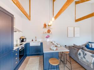 a kitchen with blue cabinets and a table and a couch at The Coach House in Whittonstall