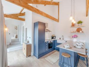 a kitchen with blue cabinets and a counter with stools at The Coach House in Whittonstall +7 photos