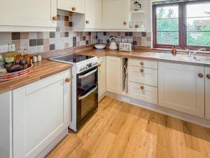 a kitchen with white cabinets and a stove top oven at The Wrens - Uk50181 in Mare Green