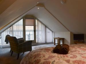 a bedroom with a bed with a chair and a window at The Hayloft in Hunstanton