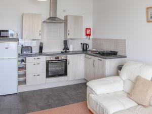 a kitchen with white cabinets and a white couch at Sands - Ukc6951 in Caernarfon