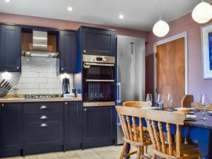 una cocina con armarios negros y una mesa con sillas en Bow Cottage, en Bourton on the Water