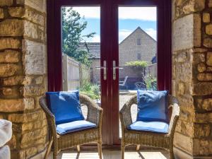 2 sillas con almohadas azules sentadas en un porche en Bow Cottage, en Bourton on the Water 13 fotos más