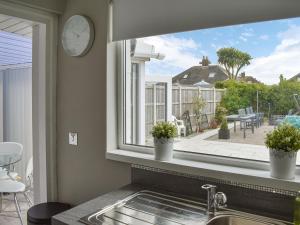 a kitchen window with two potted plants on a counter at Coleridge Lodge in Thornton