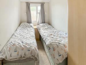 zwei Betten in einem kleinen Zimmer mit Fenster in der Unterkunft The Lodge in Chapel Saint Leonards + 3 Fotos