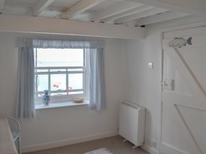 Habitación blanca con ventana y radiador en Beach Corner Cottage, en Gorran Haven 10 fotos más