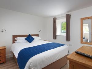 a bedroom with a bed with a blue pillow and a desk at Greylag Goose - Ukc2110 in Wroxham