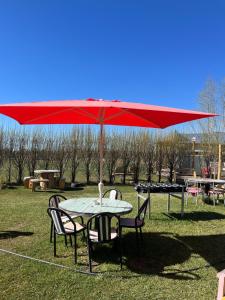 una mesa y sillas bajo una sombrilla roja en Camping Los Cardones, en Gobernador Gregores