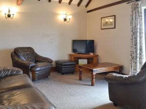 a living room with leather furniture and a flat screen tv at Baileys Barn - Ukc3738 in Bawdeswell