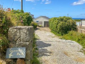 eine Schotterstraße mit einem Schild auf einem Felsen in der Unterkunft Gwennel Nook in St. Agnes 