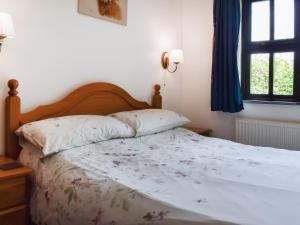 a bedroom with a bed with white sheets and a window at Dairy Cottage - Uk49834 in Lanivet