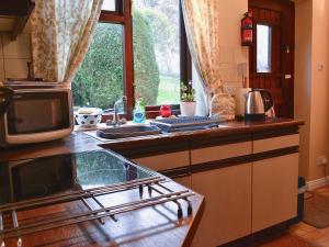 een keuken met een fornuis, een magnetron en een raam bij Rose Cottage in Cheriton Bishop