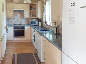 una cucina con mobili bianchi e un forno a piano cottura di Eagles Nest a St Mellion