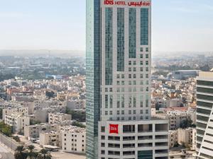a tall building with a red sign on it in a city at ibis Seef Manama in Manama