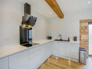 una cucina bianca con lavello e fornello di The Stone Barn 
