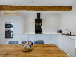una cucina con mobili bianchi e un tavolo di legno di The Stone Barn 