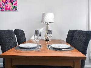 a wooden table with plates and wine glasses on it at Madeline Cottage in Clitheroe