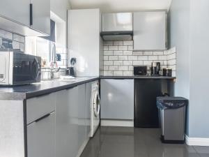 a kitchen with white cabinets and a washer and dryer at Madeline Cottage in Clitheroe