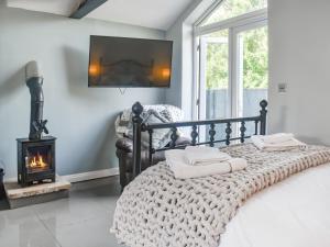 a bedroom with a bed with a fireplace and a tv at Madeline Cottage in Clitheroe +10 photos