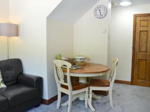 a dining room table and chairs with a clock on the wall at Percheron Cottage in Sewerby