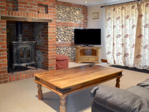 a living room with a wooden table and a fireplace at Church Farm Barn - Ukc3739 in Bawdeswell