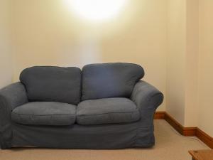 a gray couch in a room with a light on the wall at Church Farm Barn - Ukc3739 in Bawdeswell