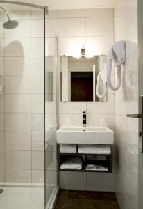 La salle de bains blanche est pourvue d'un lavabo et d'une douche. dans l'établissement Timhotel Boulogne Rives de Seine, à Boulogne-Billancourt