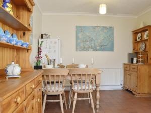 a kitchen with a table and chairs and a refrigerator at Draig's Cottage in Abergavenny