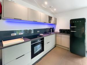 a kitchen with white cabinets and a black refrigerator at Taigh Mullach Dearg in Portree +9 photos