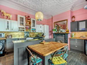 a kitchen with pink walls and a wooden table at Greystonedale Mansion Holiday Retreat in Haltwhistle
