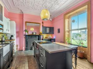 a kitchen with pink walls and a large island at Greystonedale Mansion Holiday Retreat in Haltwhistle +19 photos