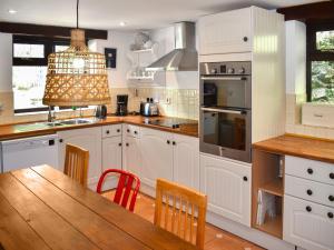 a kitchen with white cabinets and a wooden table at Townwood House in Tiverton
