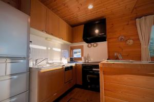 Una cocina con gabinetes de madera y un horno de estufa. en 海と田園風景を眺める高台に佇む景色抜群のログハウス #一棟貸切 #グループや家族旅行におすすめ #BBQ可のお庭 #夕陽と海が綺麗に見えるテラス #星空が綺麗 #南房総 #osora, en Minamiboso