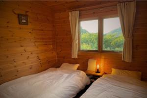 Dos camas en una habitación con ventana. en 海と田園風景を眺める高台に佇む景色抜群のログハウス #一棟貸切 #グループや家族旅行におすすめ #BBQ可のお庭 #夕陽と海が綺麗に見えるテラス #星空が綺麗 #南房総 #osora, en Minamiboso