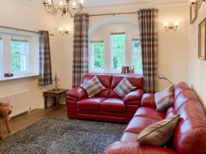 a living room with a red leather couch at Sluice Keeper's Cottage in Skelbo