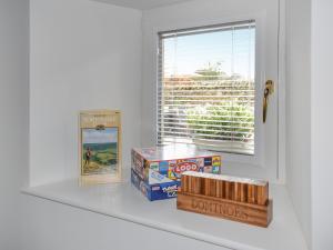 une étagère avec des livres et des boîtes à côté d'une fenêtre dans l'établissement Tosside Fold Cottage, à Tosside