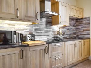 a kitchen with wooden cabinets and a brick wall at Denelea - Uk49954 in Scarborough