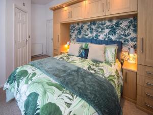a bedroom with a large bed with a blue and green bedspread at Sunnybank in Warton