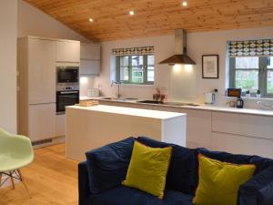 a living room with a blue couch and a kitchen at Hen Harrier Lodge-Uc3979 in Saint Columb Major