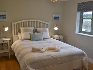 a bedroom with a large white bed with towels on it at Hen Harrier Lodge-Uc3979 in Saint Columb Major