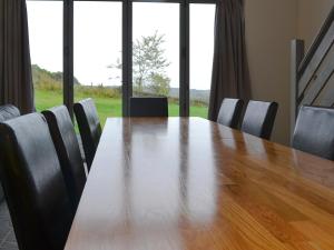 a wooden table with chairs and a large window at Heartwell Cottage in Wolsingham