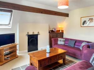 a living room with a purple couch and a tv at Sefton House Apartment in Ilkley