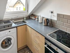 a kitchen with a sink and a washing machine at Sefton House Apartment in Ilkley