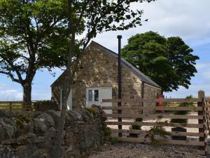 a stone barn with a fence and a tree at Sycamore Cottage in Consett +4 photos