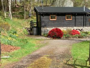a black cabin with red flowers in front of it at Squirrel View in Newtonmore +5 photos