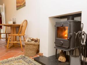 a stove in a living room with a table at Gamekeeper's Cottage in Staple