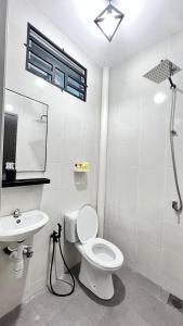 a white bathroom with a toilet and a sink at Baitul Rahah Homestay Pokok Sena in Pokok Sena
