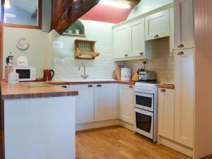 una cocina con armarios blancos y electrodomésticos blancos en Birkerthwaite Cottage-W41479, en Eskdale